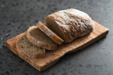 Sliced rustic style ciabatta with rye flour on olive board