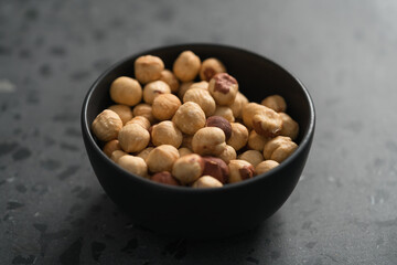 roasted hazelnuts in black bowl on terrazzo countertop