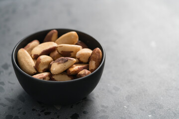 brazil nuts in black bowl on concrete background with copy space