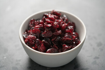 Dried cranberries in white bowl on concrete surface