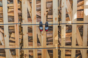 Wall consisting of a container with pieces of wood with a pair of women's shoes hanging with a combination of black, red and white color