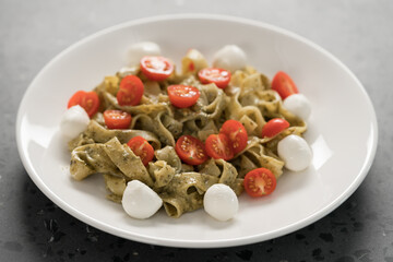 fettuccine with pesto, tomatoes and mozzarella on white plate