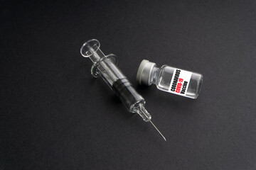 CORONAVIRUS COVID-19 VACCINE text with syringe and vials on black background. Covid-19 and Coronavirus concept