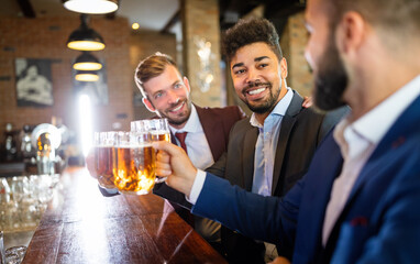 Team of colleagues socializing at the bar and drinking beers