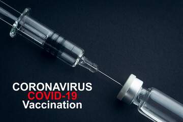 CORONAVIRUS COVID-19 VACCINATION text with syringe and vials on black background. Covid-19 and...