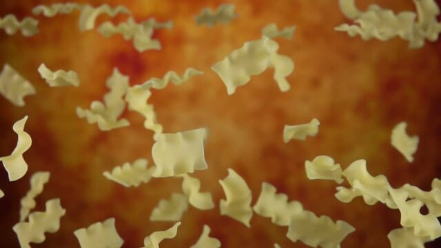 Pasta mafalde corte is flying up and rotating on a yellow ochre background in slow motion