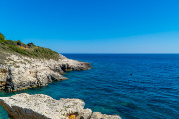 Fototapeta na wymiar Beautiful rocky Cliffs with people on boats in Kamenjak National Park, Istria, Croatia