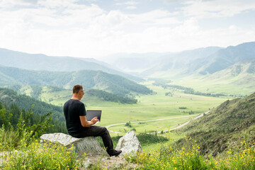  Traveler blogger work remote on netbook computer while enjoying mountain nature landscape view...