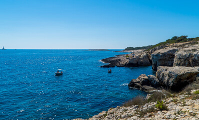 Fototapeta na wymiar People on boats near rocky cliffs in Kamenjak, Istria, Croatia