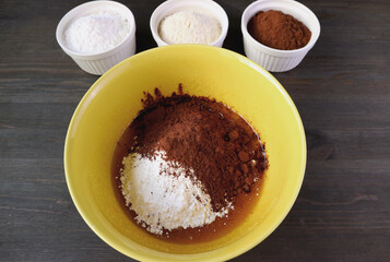 Flour and Cocoa Powder in a Mixing Bowl with Bowls of Ingredients for the Concept of COOKING HEALTHY MEAL AT HOME