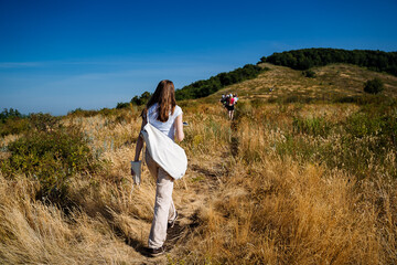 people climb up the mountain on a path among the bushes, feet close-up, shooting shoes while walking, white sneakers, outdoors, trekking, Hiking in nature, yellowed grass