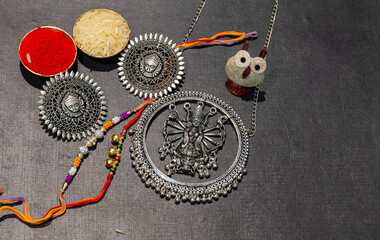 Indian festival, Raksha Bandhan background with an elegant colorful Rakhi, Gift, Rice Grains and Kumkum. A traditional Indian wrist band which is a symbol of love between Brothers and Sisters.