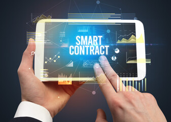 Close-up of hands holding tablet with SMART CONTRACT inscription, modern business concept