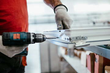 Manual worker assembling PVC doors and windows. Manufacturing jobs. Selective focus. Factory for...