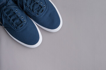 Blue textile sneakers with a white sole on a gray background. Flat lay
