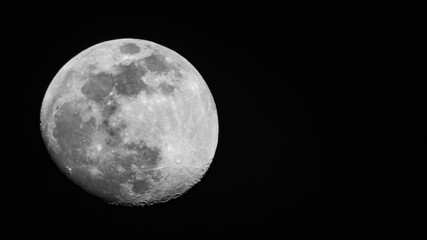 Close up moon surface, 95% Illumination of lunar disk before full moon seen from North hemispere, 700 mm focal lenght. Copy space for text on contrast black background. Astronomy, astrology, science.