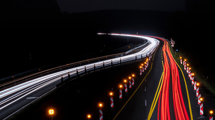 Langzeitbelichtung von einer Autobahnbrücke auf die Autobahnbaustelle bei Nacht. Stadtlichter, Sterne auf dem Himmel.