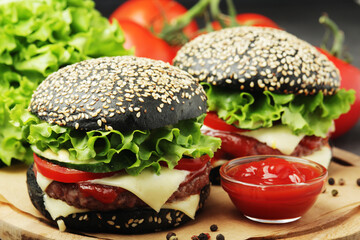 A black burger with vegetables and beef meat
