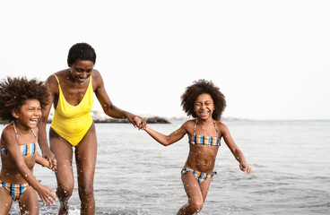 Happy African family running on the beach during summer holidays - Afro American people having fun...