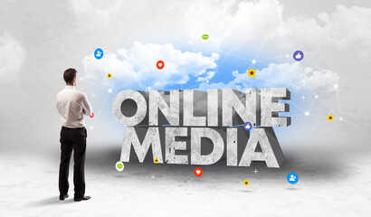 Young businessman standing in front of ONLINE MEDIA inscription, social media concept