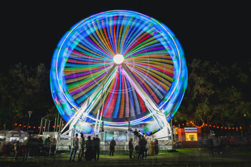 Colourful ferris wheel spinning at night 