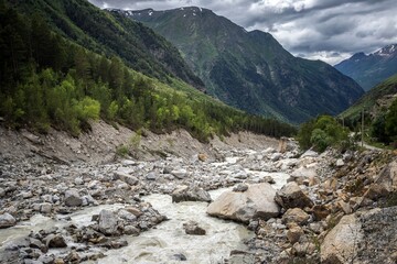 Stony riverbed of Adyl Su river, high green Caucasus mountains on the background. Kabardino-Balkaria, Russia.