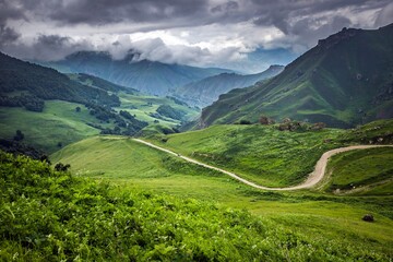Fototapeta na wymiar Wonderful landscape of green Aktoprak pass in the Caucasus, road and amazing mountains under grey clouds. Kabardino-Balkaria, Russia.