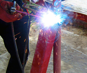 welding machine, fire, sparks, ruler, tape measure, electrode, gloves, red, metal, man's hand
