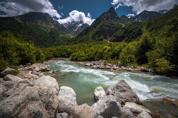Azure river Tanadon flowing among high green mountains in Digorskoe gorge. Breathtaking landscape of the Caucasus under blue sky and cold mountain river. Kabardino-Balkaria, Russia.