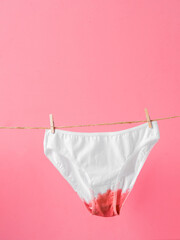 Woman's underwear on clothesline isolated on pink background, concept poster about women's health...