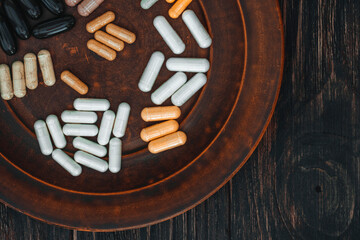 Multivitamin pills on a clay plate, on a vintage wooden table