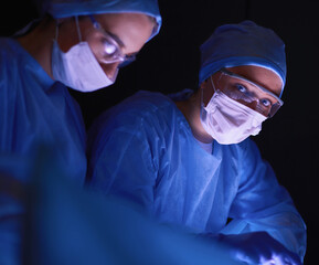 Doctors team in surgery in a dark background.