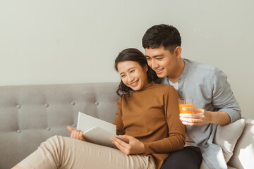 Attractive couple reading book on the sofa at home in living room