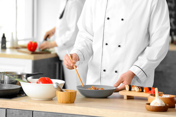 Handsome Asian chef cooking in kitchen