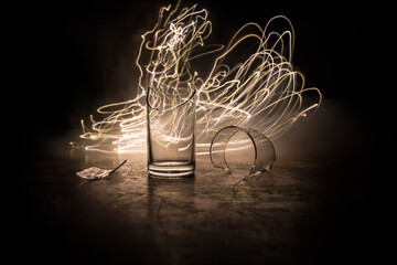 Fototapeta na wymiar Broken glasses on wooden table at dark toned background with fog. Selective focus