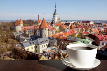 White porcelain cup of coffee or tea with view from above of red rooftops, historic old town and...