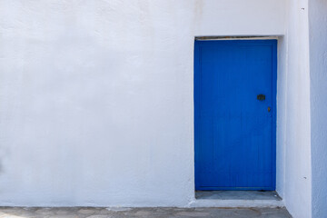 Blue color door on a white wall, greek island architecture, copy space