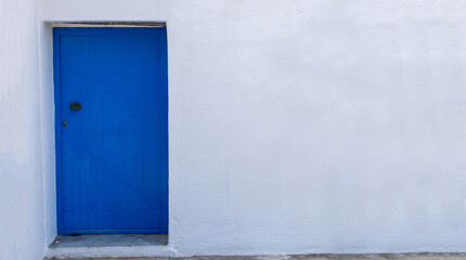 Blue color door on a white wall, greek island architecture, copy space