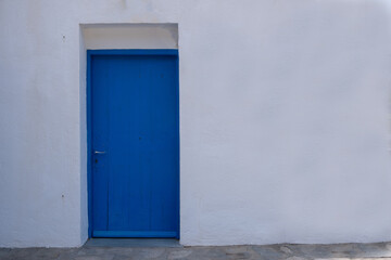 Fototapeta na wymiar Blue color door on a white wall, greek island architecture, copy space