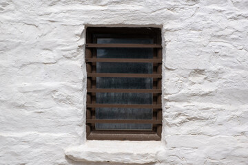 Brown color painted window with security bars on a white wall
