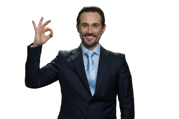 Smiling formal-dressed manager showing gesture okay. Handsome mature boss in suit isolated on white background.