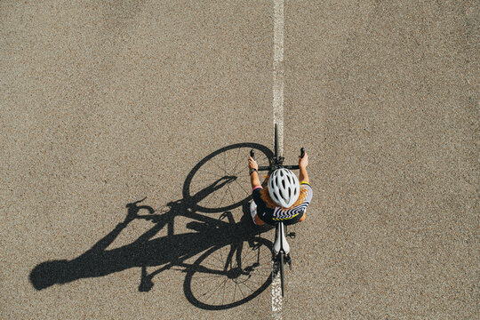 Overhead shot of a woman cycling on a professional bike in a white helmet