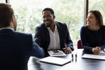 African confident executive manager welcoming client start negotiations in office. Three...