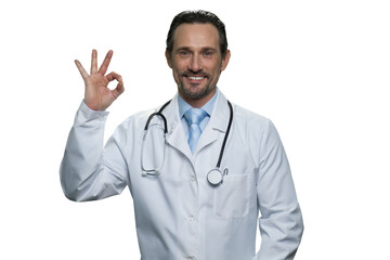 Fototapeta premium Middle-aged doctor with stethoscope is showing okay gesture. Handsome mature doctor isolated on white background.