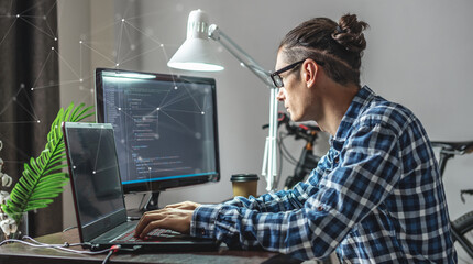 Male programmer is writing program code on a laptop at home. The concept of software development