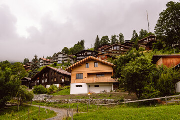 View on picturesque alpine village Wengen with typical wooden houses on overcast day in summer. Bernese Oberland, Switzerland