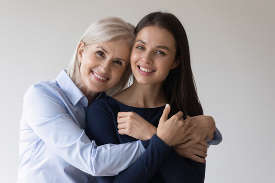 Head shot portrait mature mother adult daughter embracing looking at camera smiling feel happy enjoy moment of warmth and tenderness. Family bonds, 2 generations relatives women good relations concept
