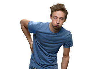 Obraz premium Teenager boy with back pain. Young guy's holding hurting back with hand against white background.