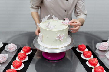 Pastry chef's hands decorate the cake with waffle butterflies