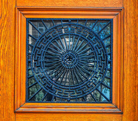 Decorative metal grid as protection for window on wooden entrance door.